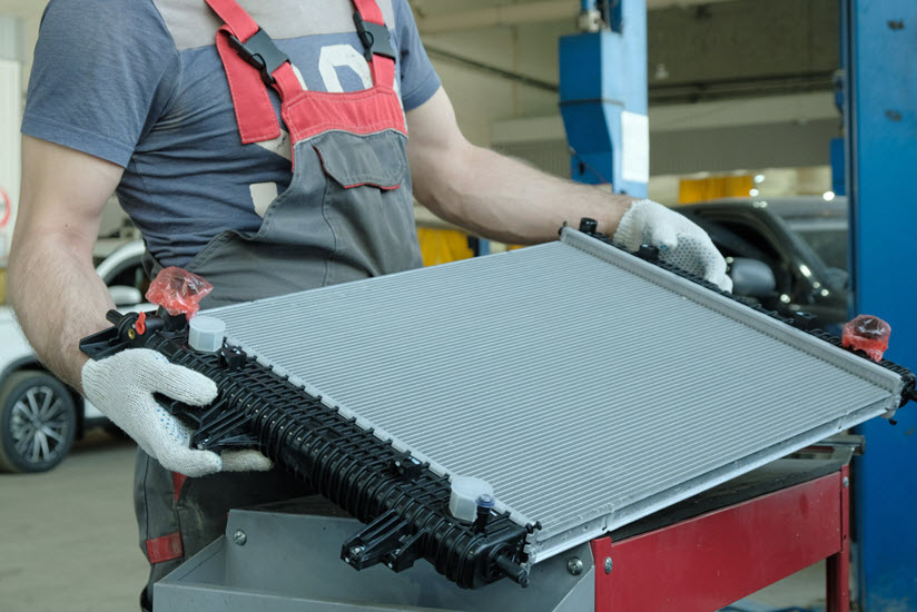 Car Mechanic Holding Engine Cooling Radiator